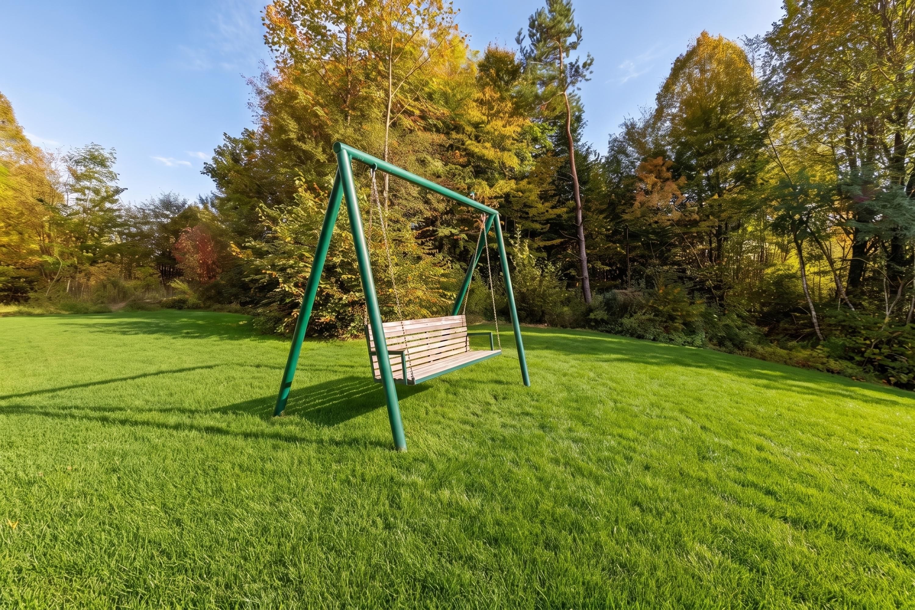 A swing set in a grassy park area with trees in the background.
