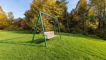 A swing set in a grassy park area with trees in the background.
