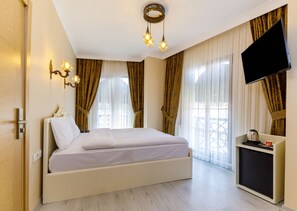 Ein Hotelzimmer mit Bett, Fernseher, Kaffeemaschine und Vorhängen.