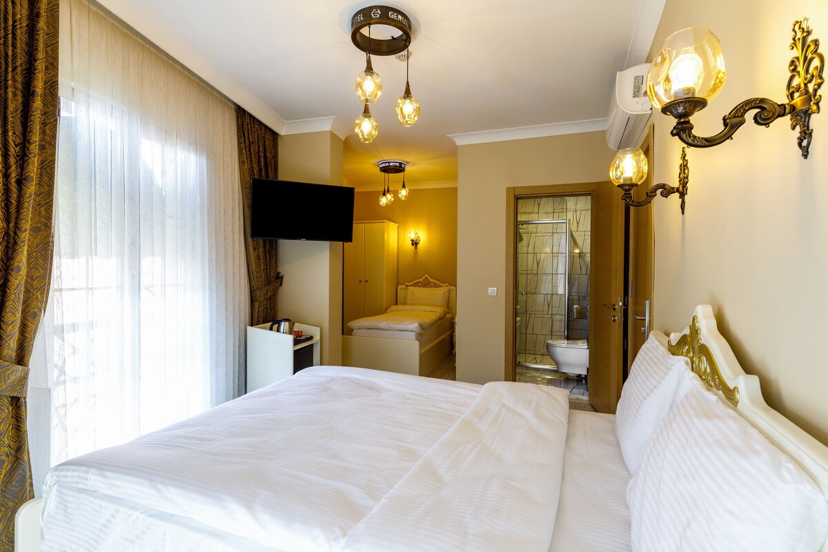 Ein Hotelzimmer mit einem großen Bett, einem an der Wand montierten Fernseher und einem durchgegangenen Tür sichtbaren Badezimmer.