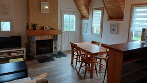 Ein gemütliches Wohnzimmer mit Kamin, Esstisch aus Holz und bequemen Sitzmöglichkeiten.