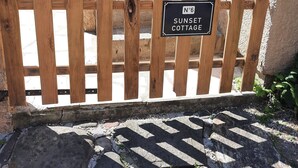 Ein hölzernes Tor mit einem Schild, auf dem 'Nº6 SUNSET COTTAGE' steht.