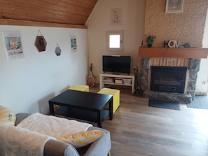 Una sala de estar acogedora con chimenea, televisor y una raqueta de tenis en un estante.