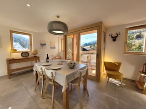 A dining area with a table set for four, wooden chairs, a globe, a clock, and a wine bottle.