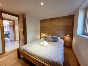 A bedroom with a wooden headboard, a bed with patterned bedding, and a nightstand.