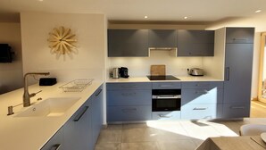 A modern kitchen with grey cabinets, a white countertop, and a built-in oven. - Bright 5-room apartment, comfort for 8 people, garage included (Les Gets)