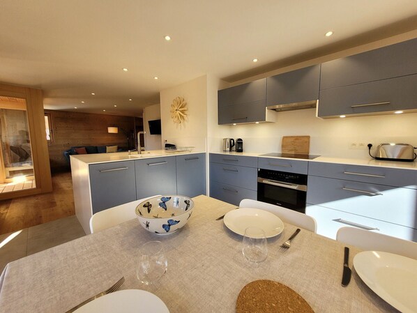A modern kitchen with grey cabinets, a central island, and a dining area with a table set for two.