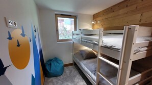 A bunk bed room with a window, a blue bean bag, and a wall mural. - Bright 5-room apartment, comfort for 8 people, garage included (Les Gets)