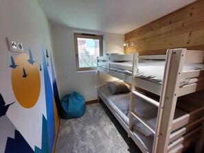 A bunk bed room with a window, a blue bean bag, and a wall mural.