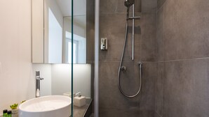 A modern bathroom with a glass shower enclosure, a white sink, and a large mirror. - Ballarò Suite Behind the Cathedral (Palermo)