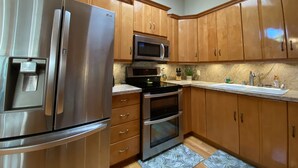 Une cuisine dotée de meubles en bois, d’appareils électroménagers en acier inoxydable, d’un four à micro-ondes, d’un four classique et d’un distributeur d’eau.