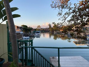 A waterfront view with a dock, boats, and a building in the background.