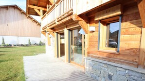 Eine Holzhütte mit Steinfundament, großen Fenstern und einer Holzterrasse.