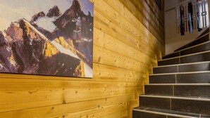 Un escalier en bois, avec une peinture représentant un paysage de montagne accrochée au mur.