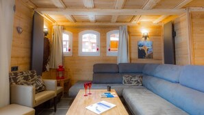 L’intérieur d’un chalet confortable, avec un canapé, un fauteuil et une table basse en bois.