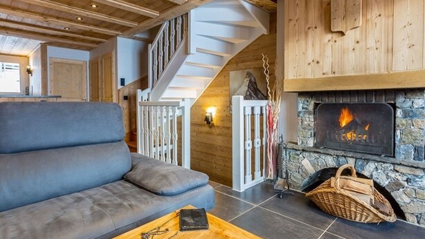 Un salon chaleureux avec un canapé gris, une table basse en bois et une cheminée.