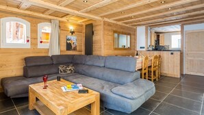 L'intérieur d'un chalet confortable, avec une grande banquette, une table basse en bois et un coin repas comprenant une table et des chaises.