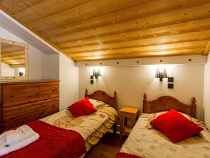 Un dormitorio acogedor con dos camas de madera, un aparador de madera y un espejo.