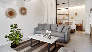 A modern living room with a grey sofa, a white coffee table, and a potted plant. - Stay 365 Heraklion Apart Hotel (Heraklion)