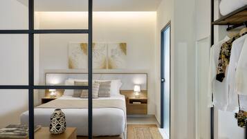 Un dormitorio de hotel moderno con una cama grande, mesitas de noche con lámparas, un jarrón decorativo y un perchero.