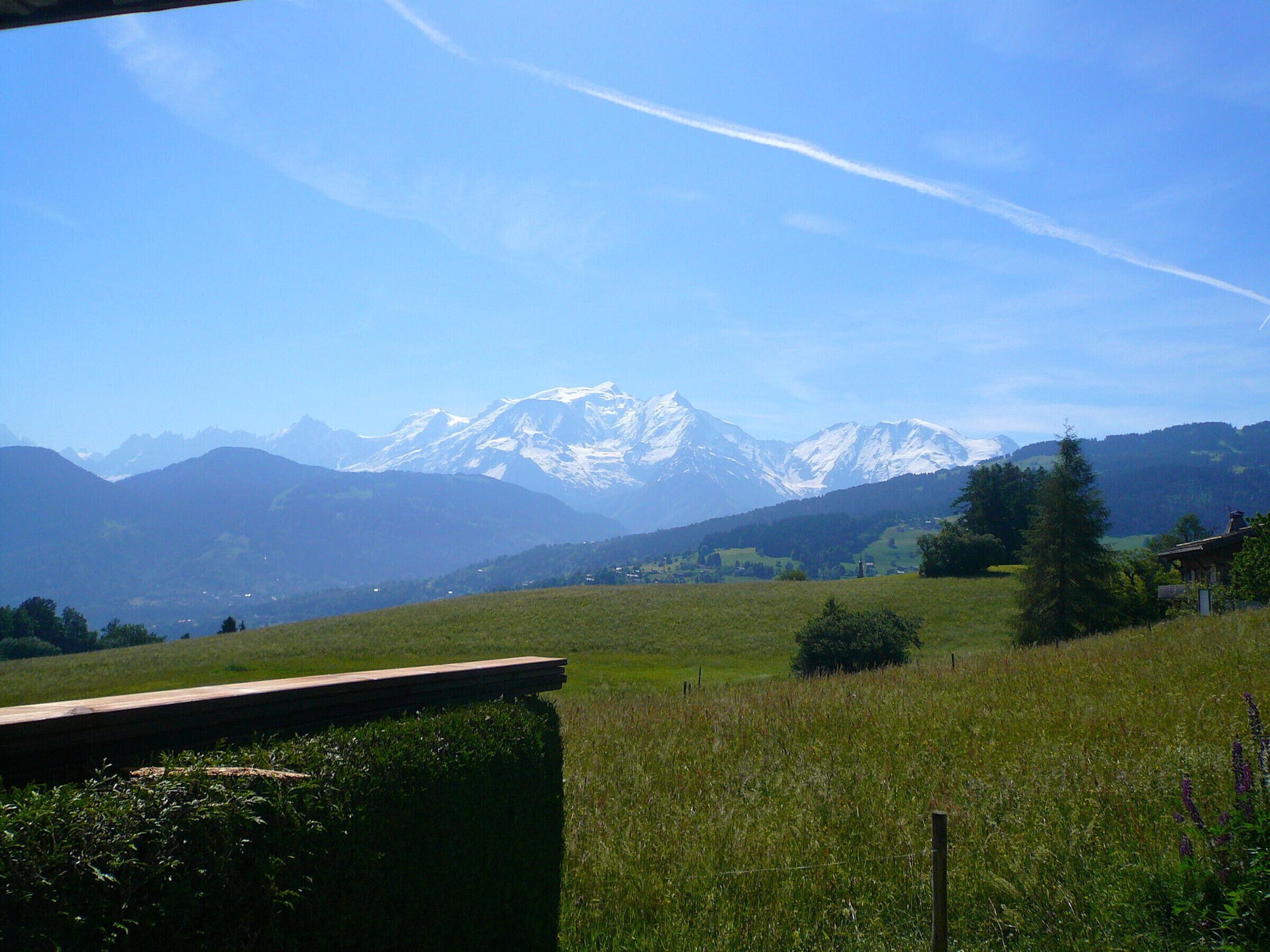 Un paysage de montagne avec un ciel dégagé et une structure en bois au premier plan.
