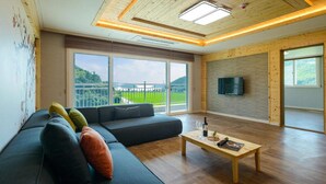 Una sala de estar moderna con un sofá seccional, una mesa de centro de madera y un televisor montado en una pared de madera.