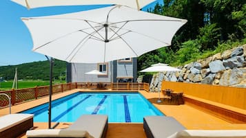 Relax by the pool surrounded by a deck with lounge chairs and umbrellas.