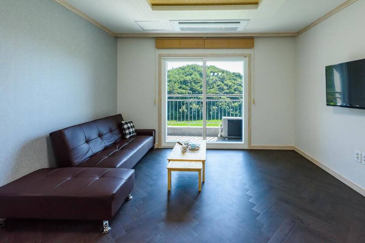 Un salon moderne avec un canapé marron foncé, une petite table en bois et un téléviseur fixé au mur.