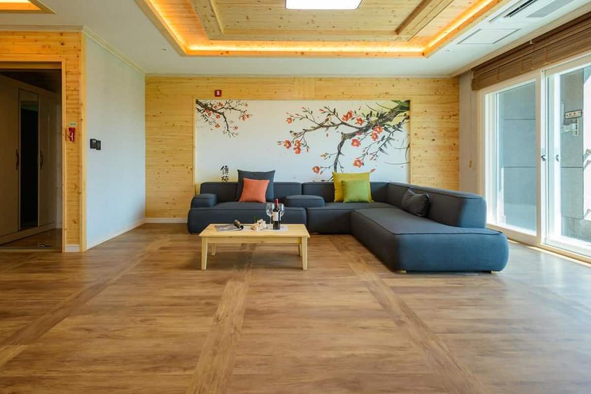 Un salon moderne avec un canapé d’angle, une table basse en bois et une grande fenêtre.