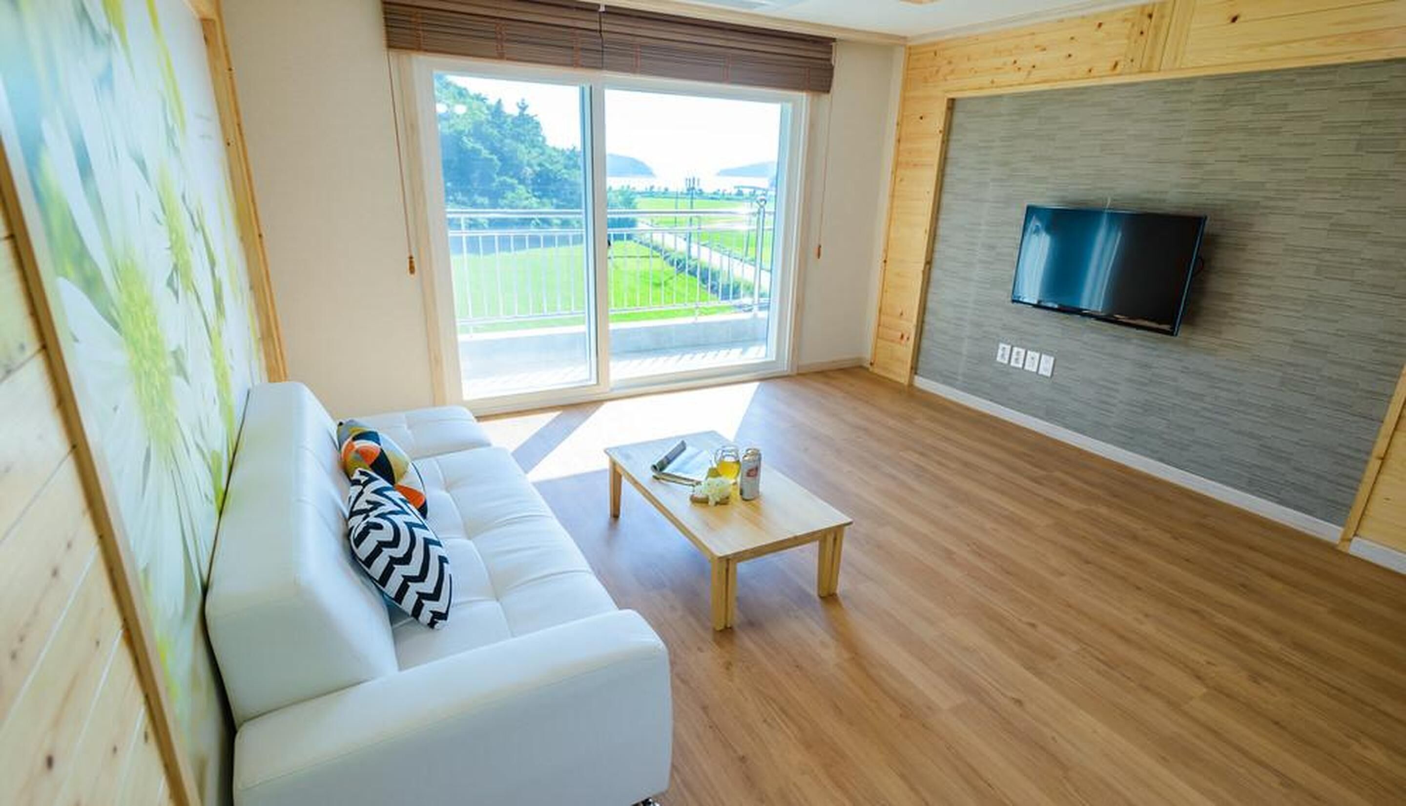 A modern living room with a white sofa, a coffee table, and a TV mounted on a grey wall.