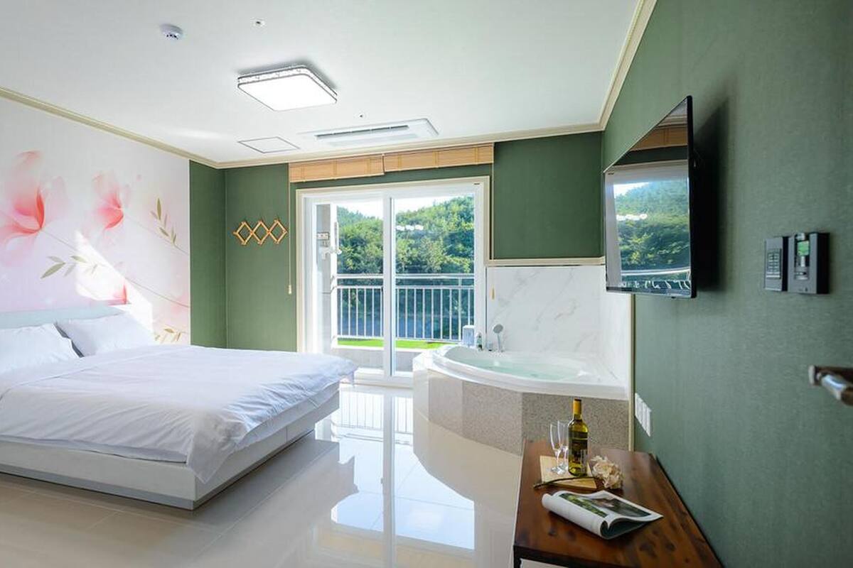 Une chambre avec un lit, une salle de bain avec un lavabo et un miroir, et un balcon avec vue.