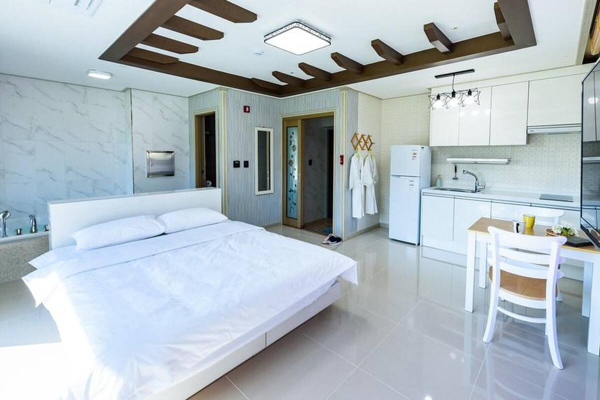 Une chambre d’hôtel moderne dotée d’un grand lit, d’une kitchenette et d’une salle de bain.