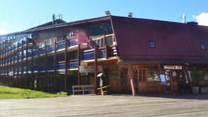 A multi-story building with balconies, a wooden deck, and a snack bar. - 3-room ski-in/ski-out apartment for 7 in Arc 1800 (Les Arcs 1800)