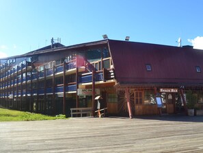 Um edifício com vários andares, varandas, um deck de madeira e um bar de petiscos.