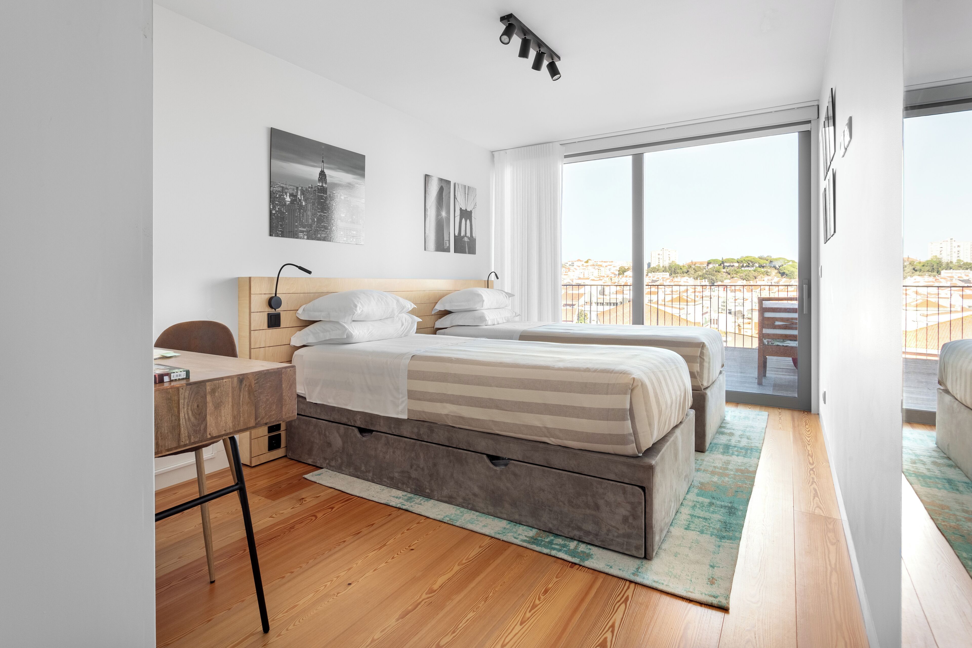 Un dormitorio moderno con una cama grande, un escritorio y vistas de la ciudad desde un balcón.