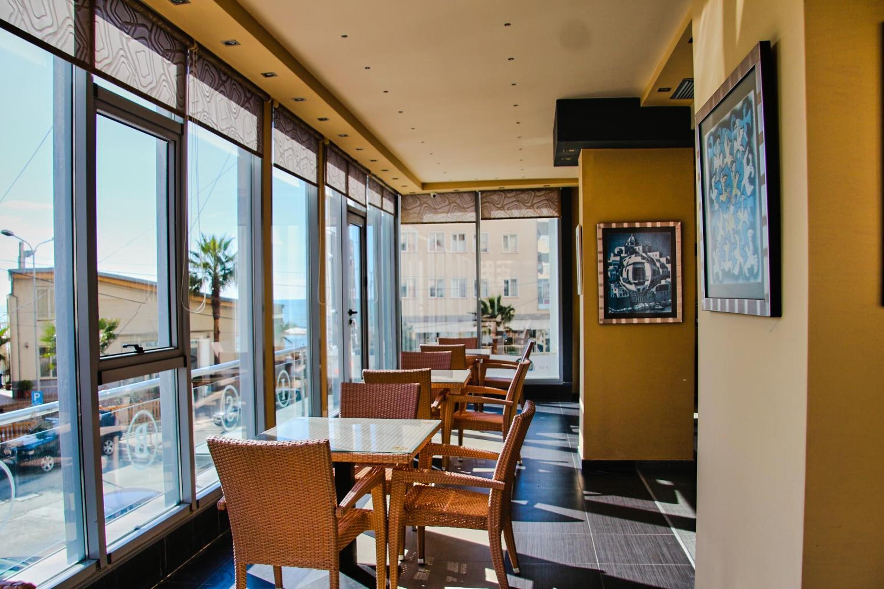 A restaurant with large windows, wicker chairs, and tables.