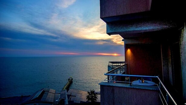 Uma varanda com vista para o mar e para o pôr do sol.