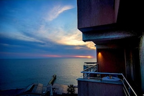A balcony with a view of the sea and sunset.