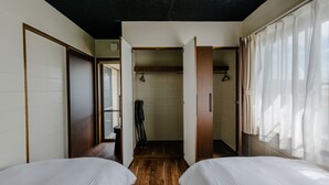 A hotel room with two beds, wooden flooring, a bathroom with a shower, and a view of the street. - Lego (Uruma)