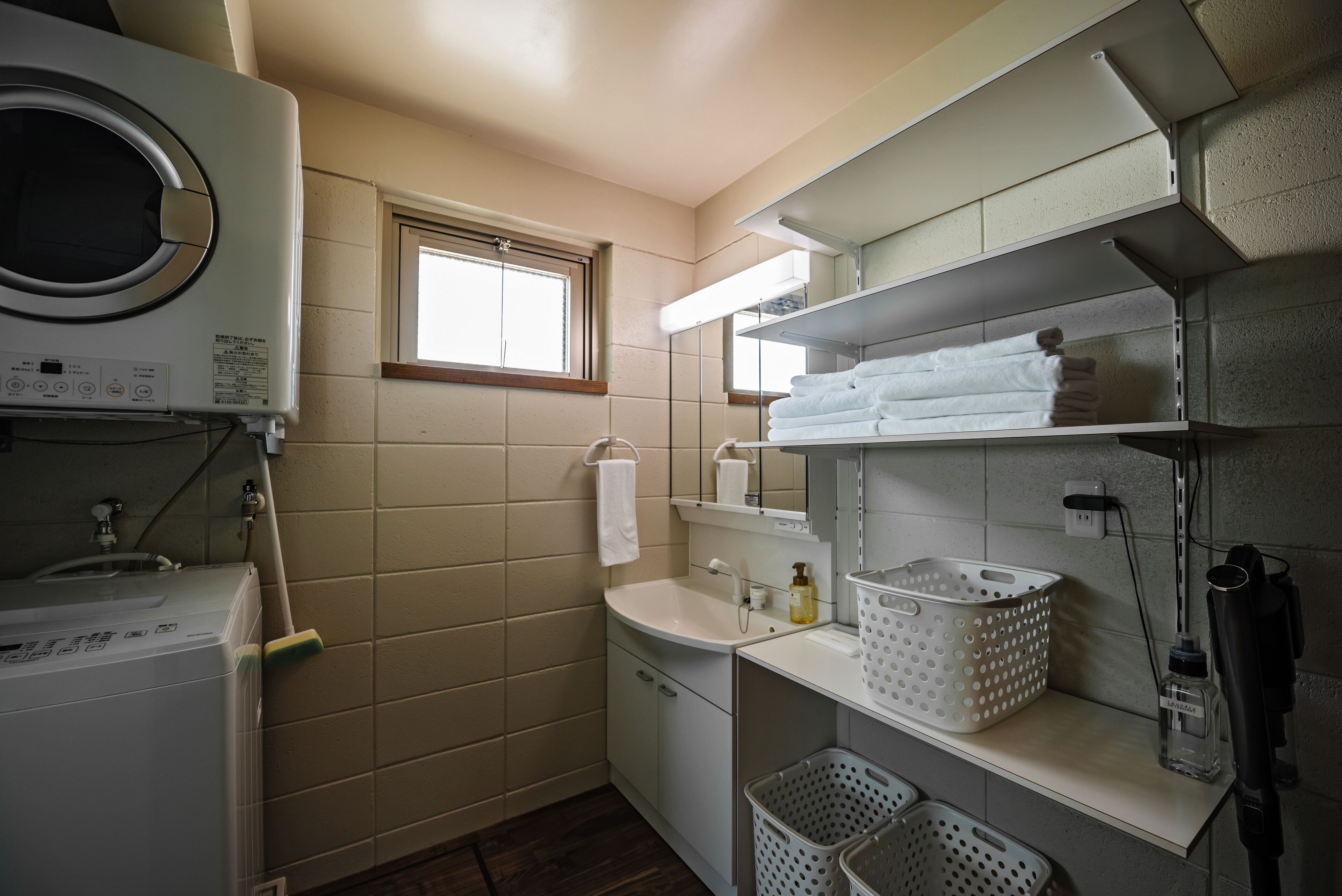 A compact laundry room with a washing machine, a sink, and a window.