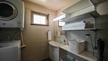 A compact laundry room with a washing machine, a sink, and a window.