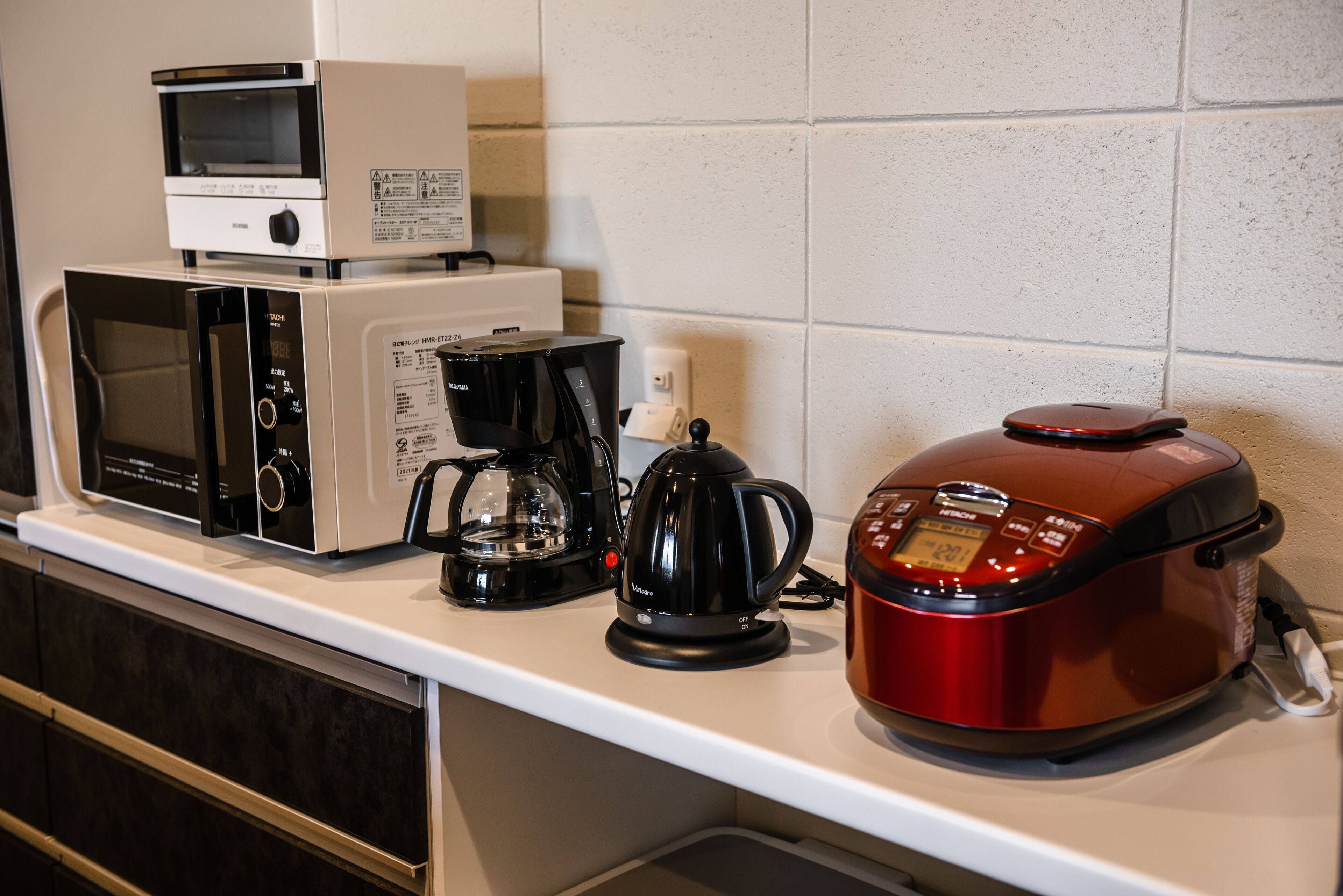 A kitchen counter with a microwave, coffee maker, and rice cooker.