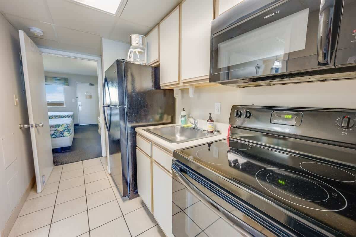 A compact kitchen with a refrigerator, microwave, and stove.
