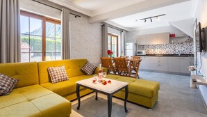 Una sala de estar moderna con un sofá amarillo, una mesa de comedor y una cocina al fondo.