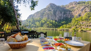 A table set for a meal with various dishes and a view of a lake and mountains. - Villa Elmas Paradise (Ortaca)