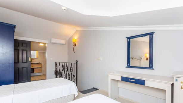 Un dormitorio con dos camas, un escritorio, un aparador, un espejo y una puerta que da a un baño.