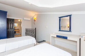 A bedroom with two beds, a desk, a dresser, a mirror, and a door leading to a bathroom. - Villa Derya Paradise (Ortaca)