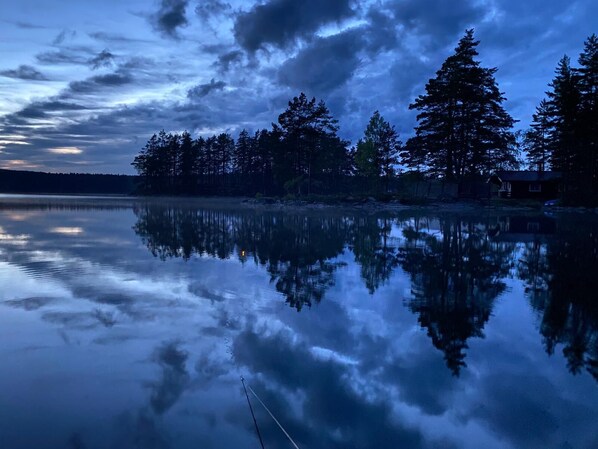 A calm lake with reflections of trees and a cabin. - Exclusive and modern holiday home "Lilla älg" right on the lake 365 days a year! (Arvika)