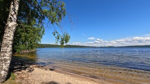 Ein See mit klarem Wasser, umgeben von Bäumen und einem sandigen Ufer.