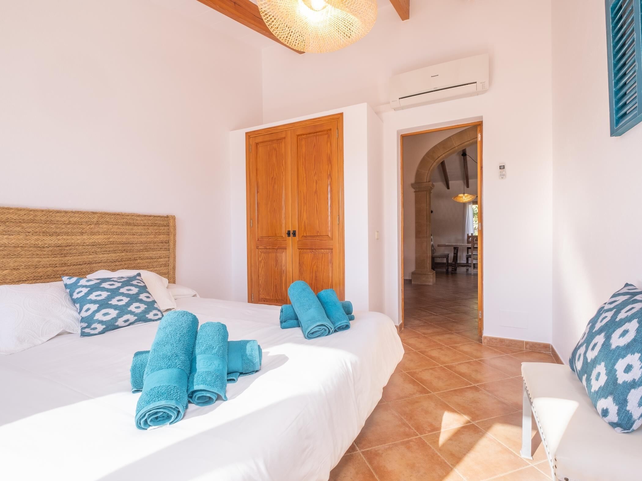 A bedroom with two beds, a wooden door, and a view into another room.